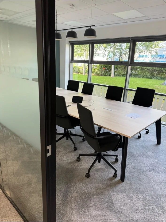 Meeting table and chairs beside large windows at Green Earth, Birchwood Park