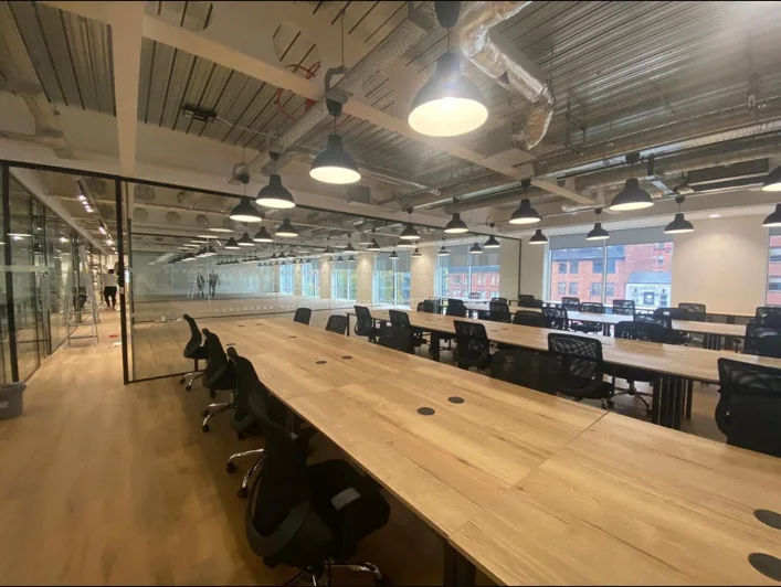 Long shared desks beneath exposed services at The Lincoln in Manchester